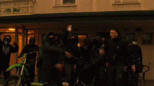 People in Front of Building With Mask Saying A