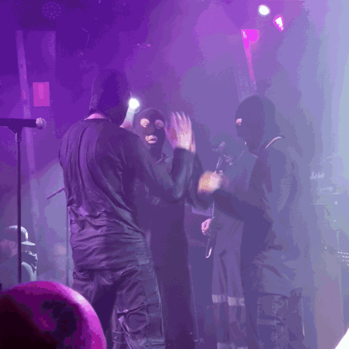 People in Ski Masks on Stage With Purple Lights