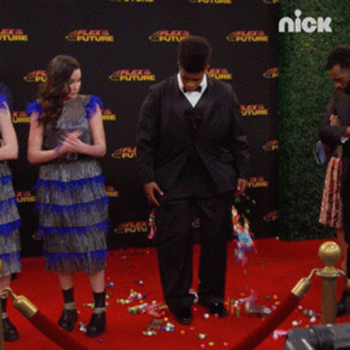 people on a red carpet in front of a wall that says nick