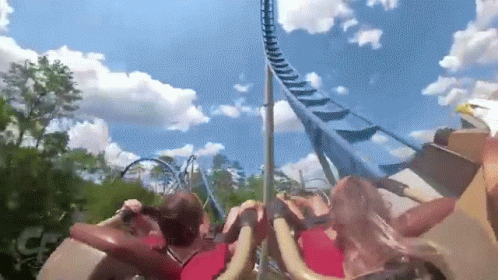 People Riding Roller Coaster With Blue Sky and Clouds