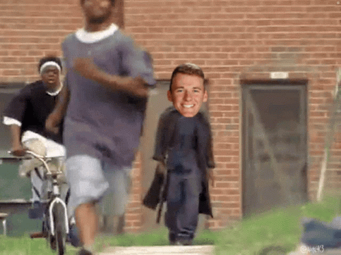 People Running in Front of Brick Building With Man on Back