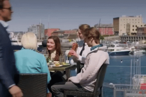 People Sitting At Table In Harbor GIF