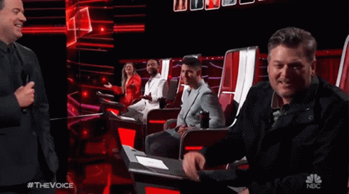 People Sitting in Chairs on Stage With NBC Logo