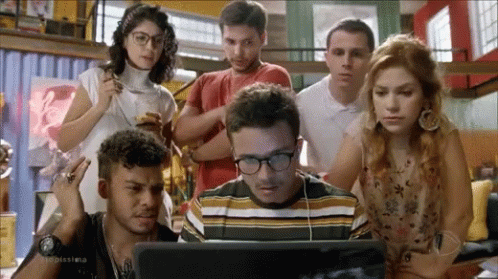 People Standing Around Man Looking at Laptop