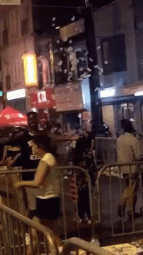 People Standing by Fence on Crowded Street