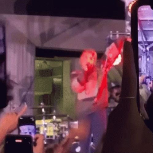 People Taking Pictures Of Man In Red Costume On Stage GIF