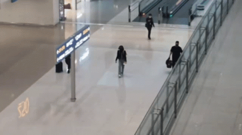 People Walking In An Airport With A Sign That Says ' Arrivals ' GIF