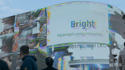 People Walking In Front Of A Billboard That Says Bright On It GIF