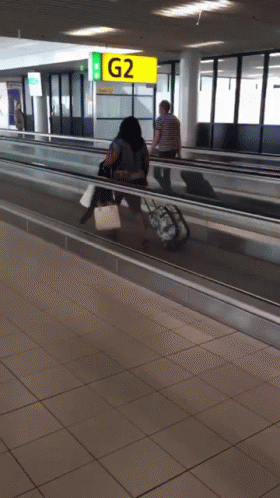 People Walking on Escalator With G2 Sign
