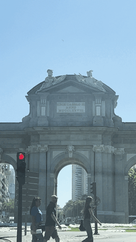 People Walking Under Stone Archway Puerta de Arco de Madrid