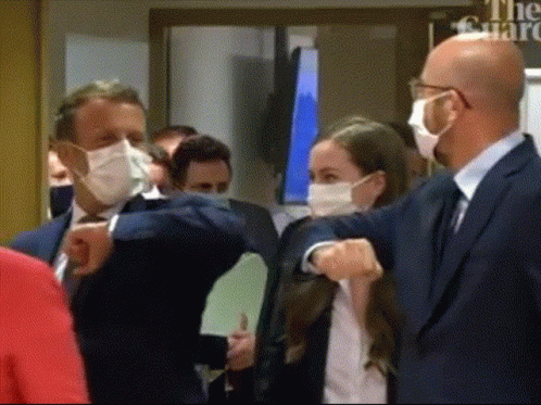 People Wearing Masks in Front of Guard Sign
