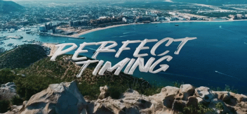 perfect timing is written on a rocky hill overlooking the ocean