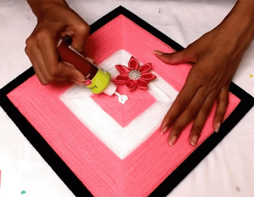 Person Applying Glue to Pink Square With Red Flower