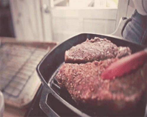 Person Cooking Steak in Pan