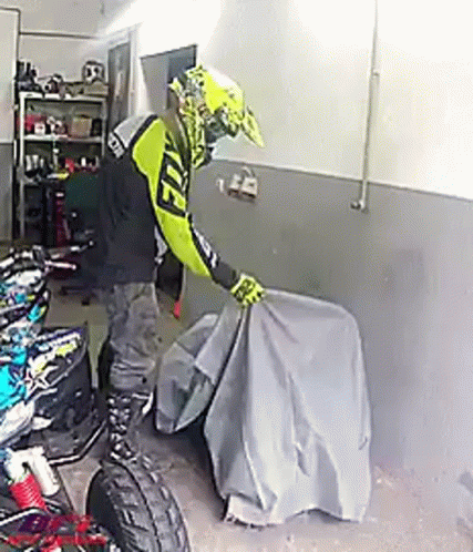 Person Covering Motorcycle in Garage