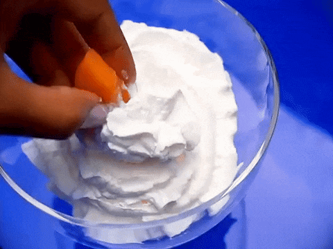 Person Cracking Egg Into Whipped Cream Bowl