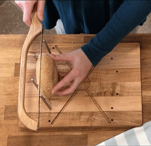 Person Cutting Bread on Wooden Board
