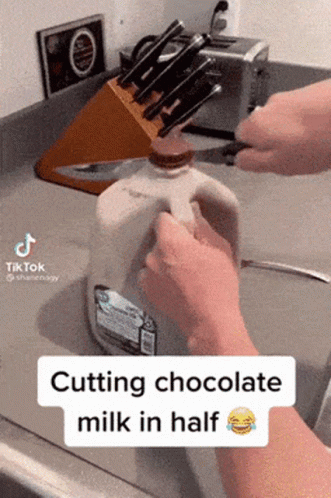 Person Cutting Chocolate Milk in Half With Knife