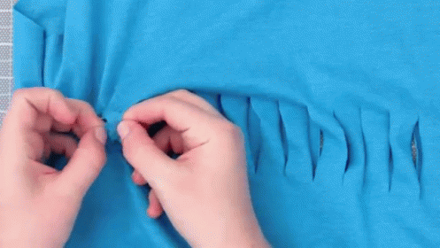 Person Cutting Hole in Blue T-Shirt with Scissors