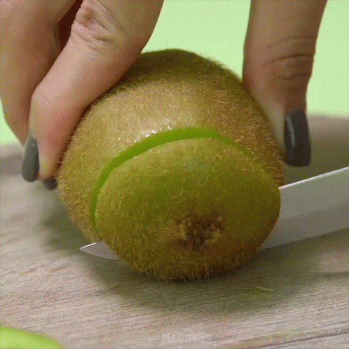 Person Cutting Kiwi in Half with Knife