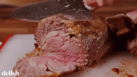 Person Cutting Large Piece Of Meat On Cutting Board With Delish GIF
