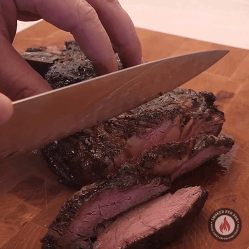 Person Cutting Meat on Wooden Board