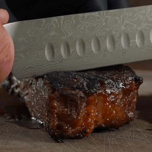 Person Cutting Meat With Patterned Knife GIF