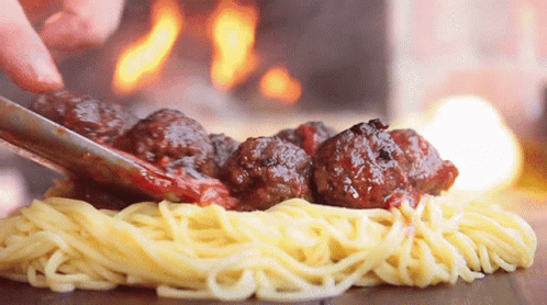 Person Cutting Meatballs on Spaghetti