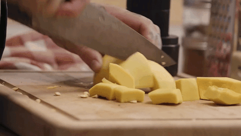 Person Cutting Yellow Cheese on Cutting Board