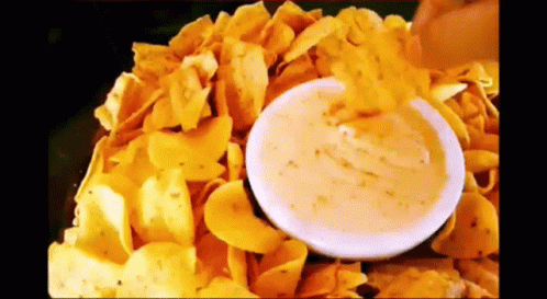 Person Dipping Chip into Cheese Sauce