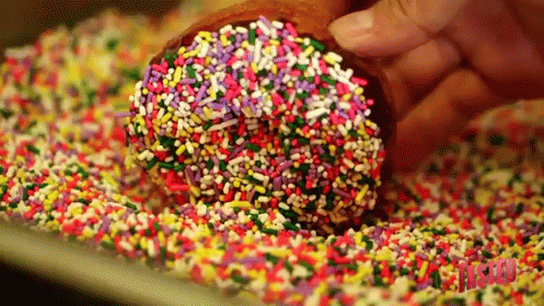 Person Dipping Donut in Sprinkles