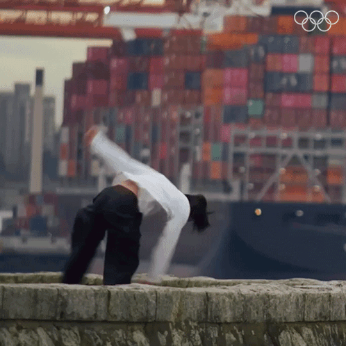 Person Doing Handstand In Front Of Large Ship GIF