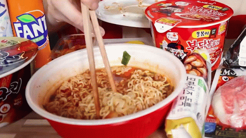 Person Eating Noodles With Chopsticks In Red Bowl Next To Fanta GIF