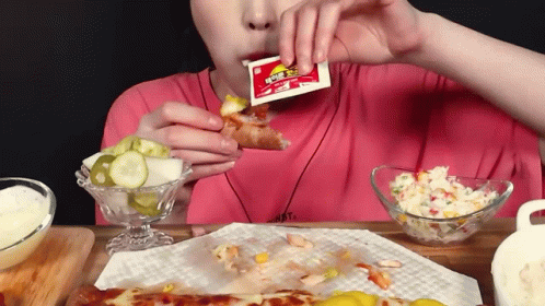 Person Eating Pizza Slice With Ketchup Packet