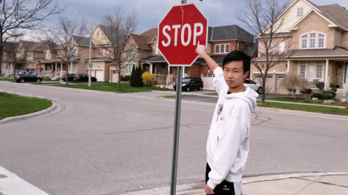 Person Hanging Upside Down Next to Red Stop Sign