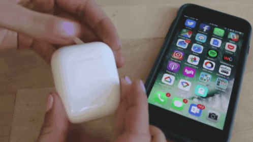 Person Holding Airpod Beside Phone With Apps