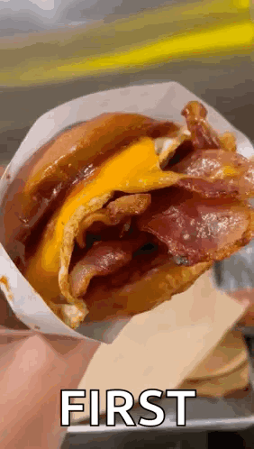 Person Holding Bacon Cheese Sandwich in Bag With First