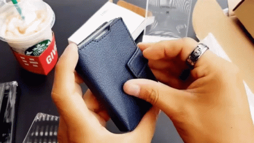 Person Holding Blue Wallet in Front of Starbucks Cup