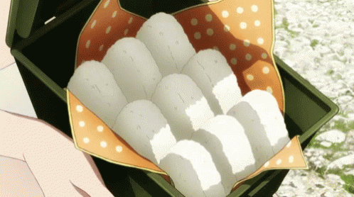 Person Holding Box of Rice Balls on Polka Dot Cloth