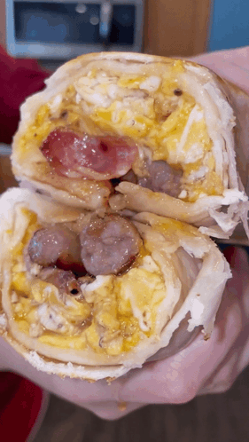 Person Holding Burrito With Eggs and Sausage