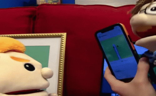 Person Holding Cell Phone Before Two Puppets