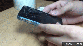 Person Holding Cell Phone With Broken Screen On Table GIF