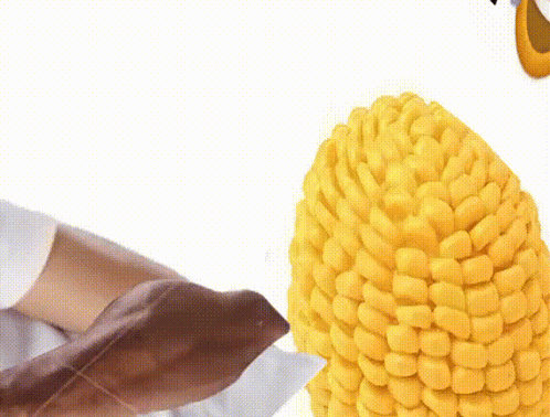 Person Holding Corn on the Cob With Knife