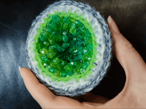 Person Holding Crocheted Object With Green Beads GIF