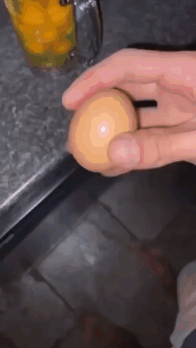 Person Holding Egg in Front of Orange Juice