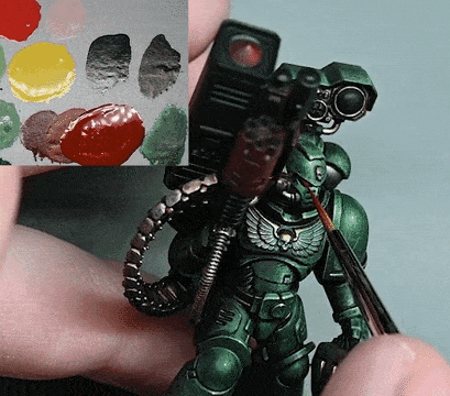 Person Holding Green Robot and Brush Next to Paint Palette
