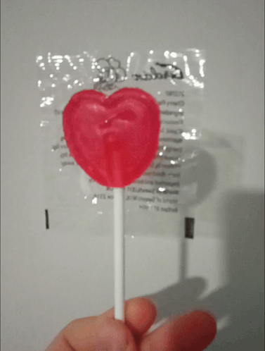 Person Holding Heart Lollipop In Front Of Candy Bag GIF