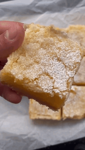 Person Holding Lemon Bar with Powdered Sugar