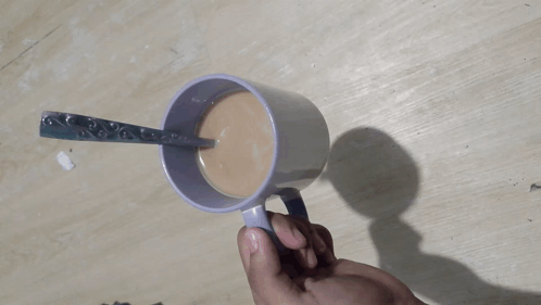 Person Holding Mug of Coffee With Spoon