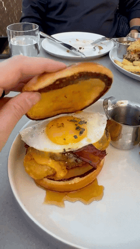 Person Holding Sandwich with Fried Egg and Bacon